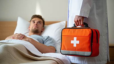 Рядом с кроватью пациента стоит врач в белом халате